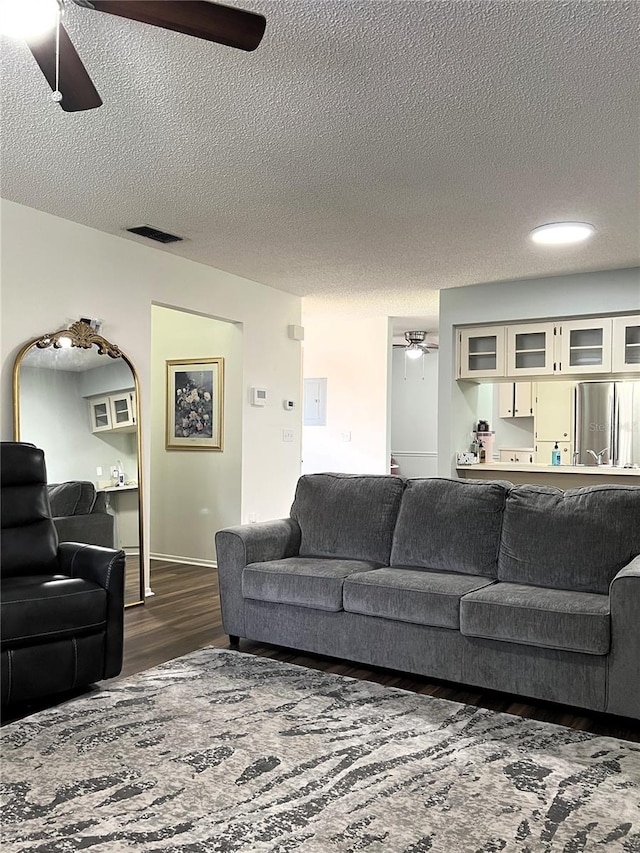 7721 Hillside Ct Unit 203, Hudson, FL 34667 - living room featuring a ceiling fan, a textured ceiling, and dark wood-style floors