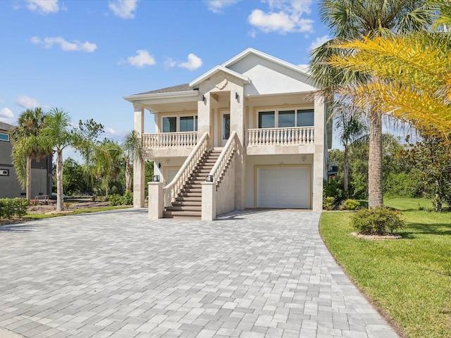 5621 Egrets Pl, New Port Richey, FL 34652 - coastal inspired home with stairs, decorative driveway, a garage, stucco siding, and covered porch