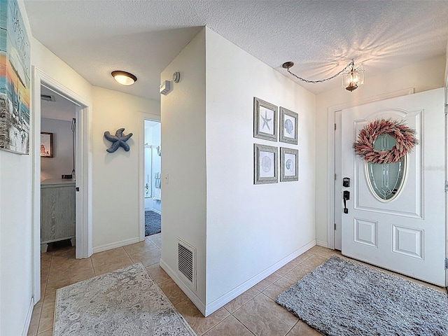 12817 2nd Isle, Hudson, FL 34667 - entrance foyer featuring light tile patterned floors, a textured ceiling, and a chandelier