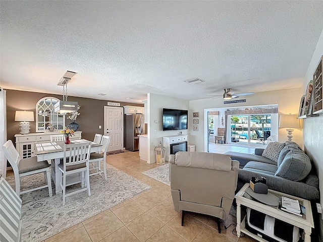 12817 2nd Isle, Hudson, FL 34667 - living room featuring light tile patterned floors, a ceiling fan, and a textured ceiling