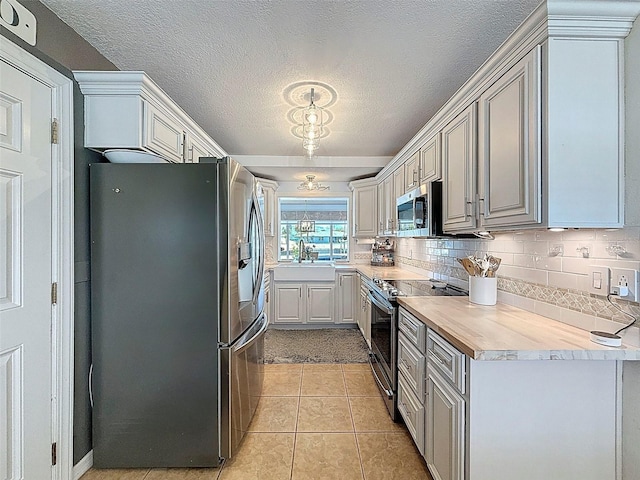 12817 2nd Isle, Hudson, FL 34667 - kitchen featuring appliances with stainless steel finishes, decorative backsplash, light tile patterned flooring, light countertops, and a textured ceiling