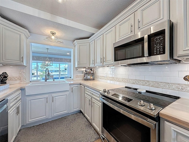 12817 2nd Isle, Hudson, FL 34667 - kitchen featuring appliances with stainless steel finishes, a textured ceiling, light countertops, tasteful backsplash, and white cabinets