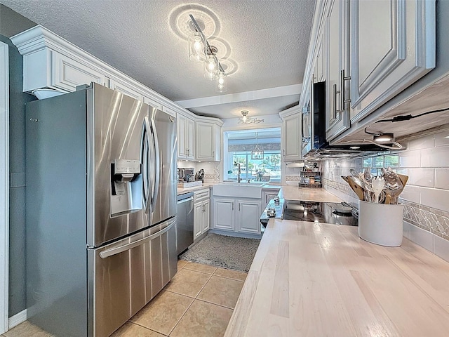 12817 2nd Isle, Hudson, FL 34667 - kitchen with appliances with stainless steel finishes, light countertops, light tile patterned floors, a textured ceiling, and decorative backsplash