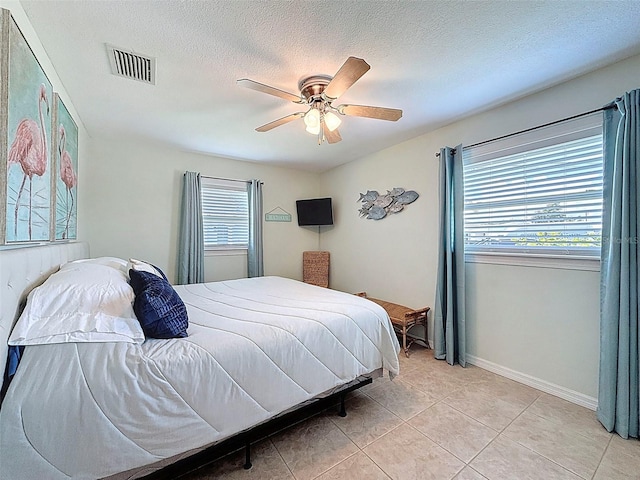 12817 2nd Isle, Hudson, FL 34667 - bedroom with light tile patterned flooring, multiple windows, a ceiling fan, and a textured ceiling