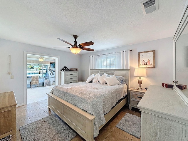 12817 2nd Isle, Hudson, FL 34667 - bedroom featuring multiple windows, light tile patterned flooring, ceiling fan, and a textured ceiling