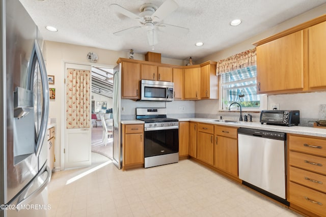 kitchen with ceiling fan, a textured ceiling, sink, and appliances with stainless steel finishes