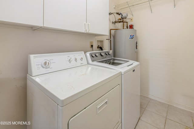 clothes washing area featuring light tile patterned floors, washing machine and dryer, baseboards, water heater, and cabinet space