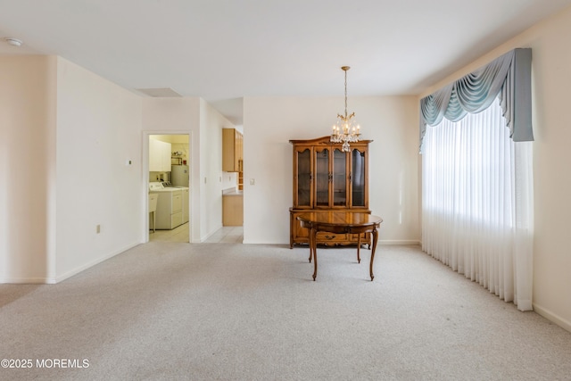 unfurnished room with a chandelier, separate washer and dryer, light carpet, and baseboards