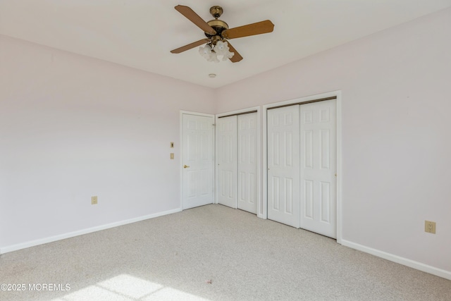 unfurnished bedroom with ceiling fan, carpet floors, two closets, and baseboards