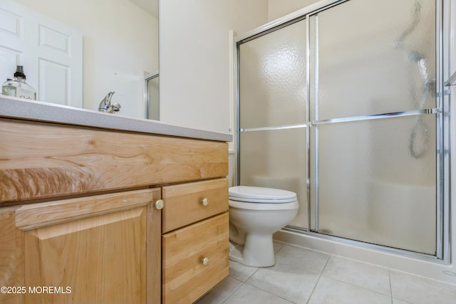 bathroom featuring vanity, a shower stall, toilet, and tile patterned floors