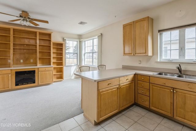 kitchen featuring light colored carpet, a peninsula, light countertops, open shelves, and a sink