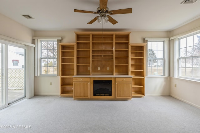 unfurnished living room featuring light colored carpet, visible vents, a ceiling fan, a glass covered fireplace, and baseboards