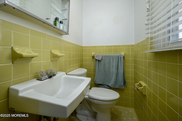 bathroom featuring toilet, sink, and tile walls