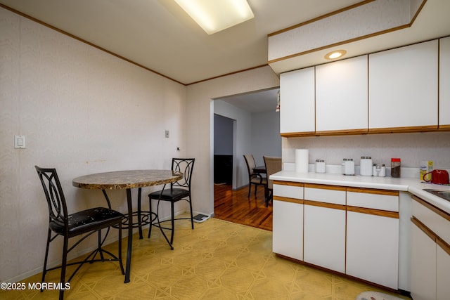 kitchen with a kitchen breakfast bar, white cabinetry, and crown molding