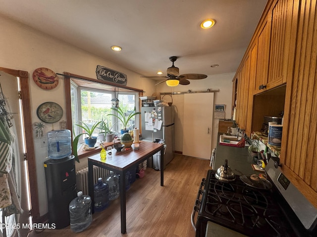 115 Washington St, Long Branch, NJ 07740 - kitchen with a barn door, stainless steel appliances, light wood-style floors, a sink, and brown cabinets