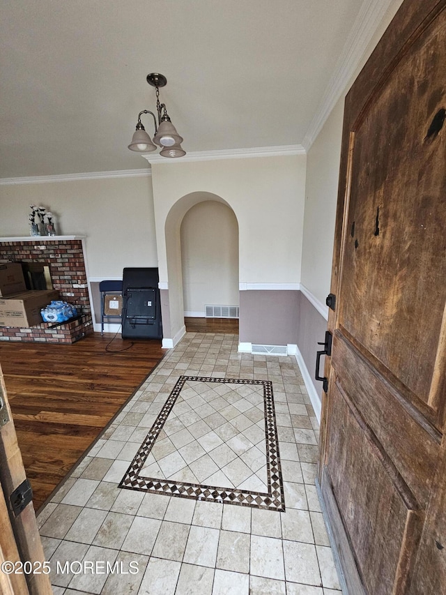 tiled foyer entrance featuring crown molding and an inviting chandelier