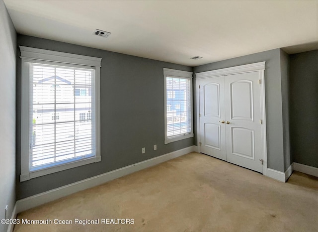 unfurnished bedroom with light carpet and multiple windows