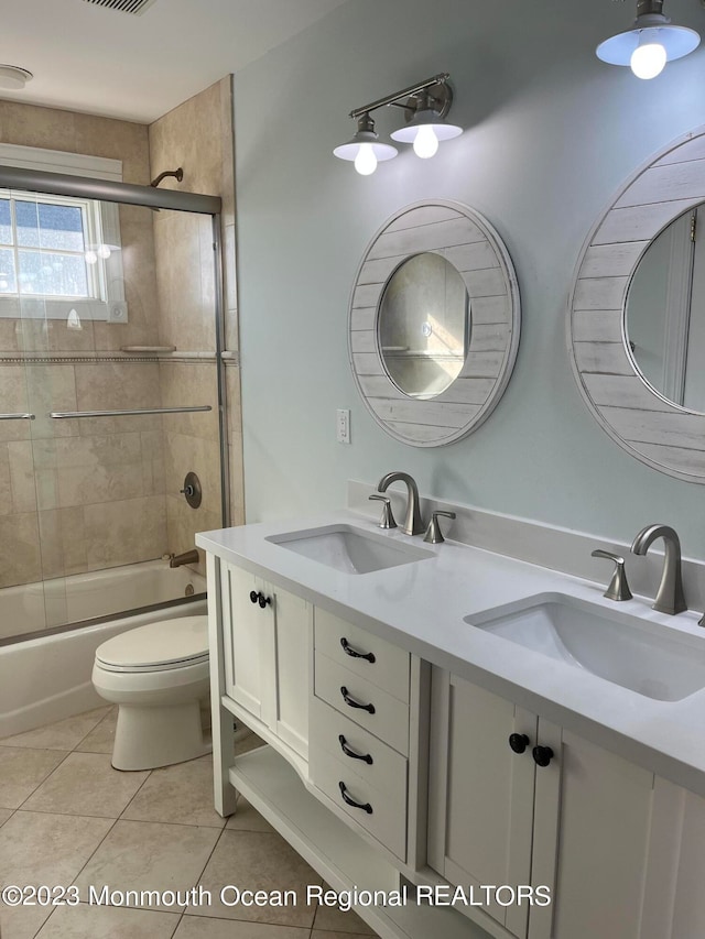 full bathroom featuring tile flooring, shower / bath combination with glass door, double sink vanity, and toilet