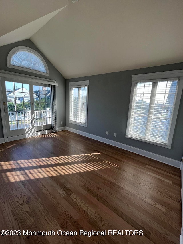 spare room with dark wood-type flooring and lofted ceiling