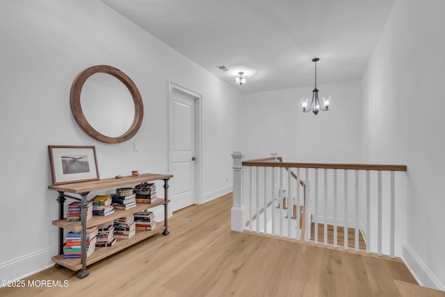 hallway featuring light hardwood / wood-style flooring and an inviting chandelier