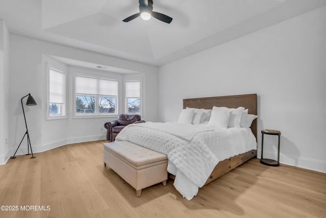 bedroom featuring light hardwood / wood-style flooring, a raised ceiling, and ceiling fan