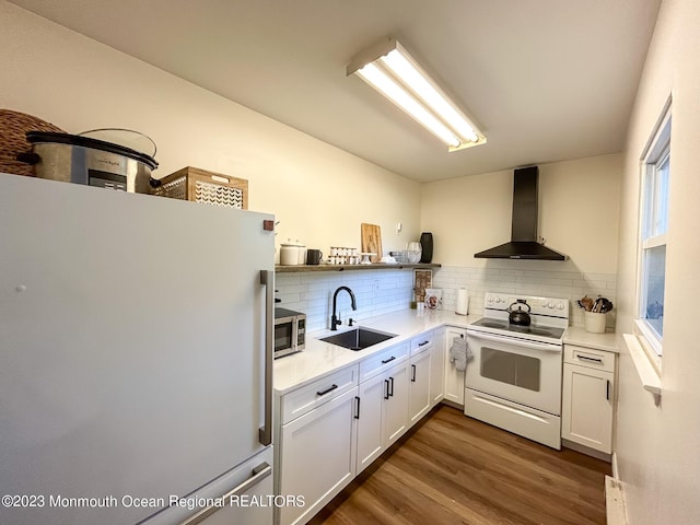 kitchen featuring a sink, backsplash, wall chimney range hood, white appliances, and open shelves