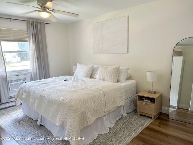 bedroom featuring cooling unit, a ceiling fan, wood finished floors, baseboards, and arched walkways