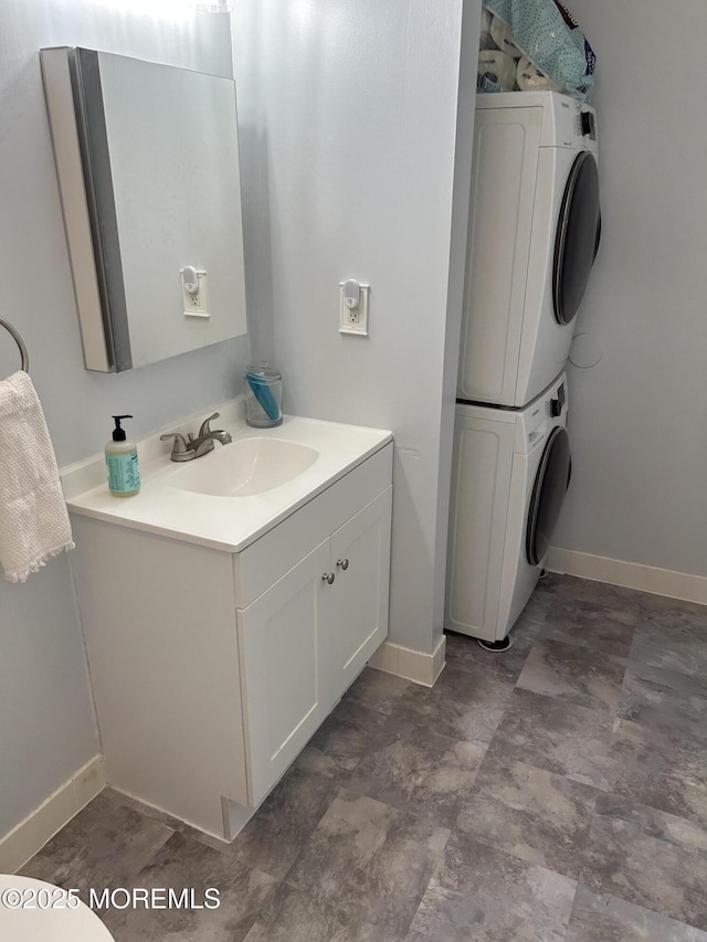 bathroom with stacked washer and clothes dryer, vanity, and baseboards