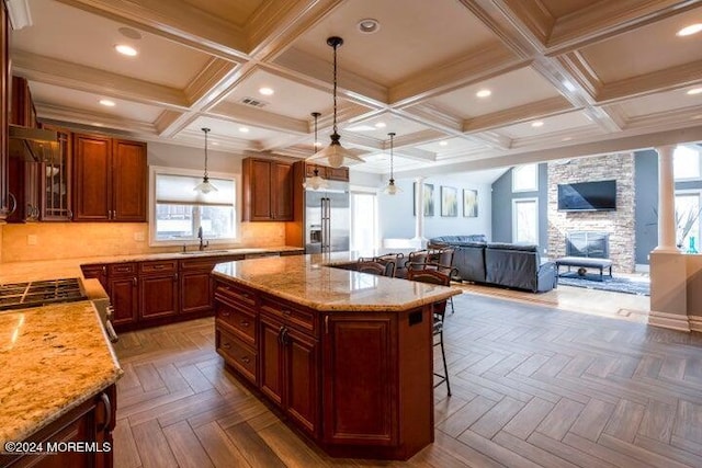 kitchen with built in fridge, a kitchen island, a breakfast bar area, and dark parquet floors