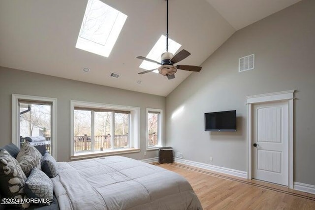 bedroom featuring ceiling fan, a skylight, high vaulted ceiling, and light hardwood / wood-style flooring