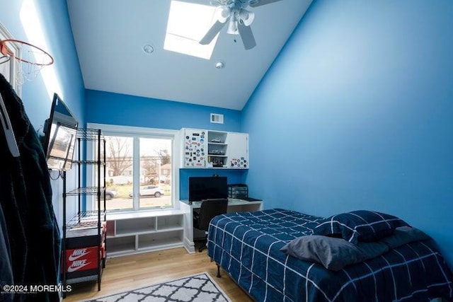 bedroom featuring ceiling fan, high vaulted ceiling, light hardwood / wood-style floors, and a skylight