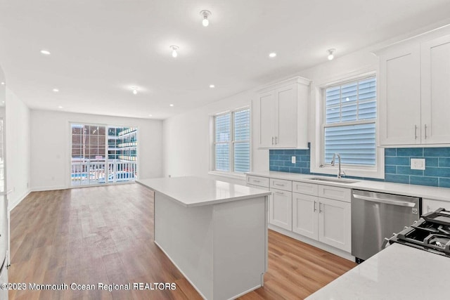 kitchen with white cabinets, a healthy amount of sunlight, light hardwood / wood-style floors, and tasteful backsplash