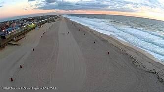 aerial view at dusk with a water view and a beach view