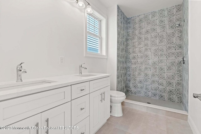 bathroom with a tile shower, tile flooring, toilet, and dual bowl vanity