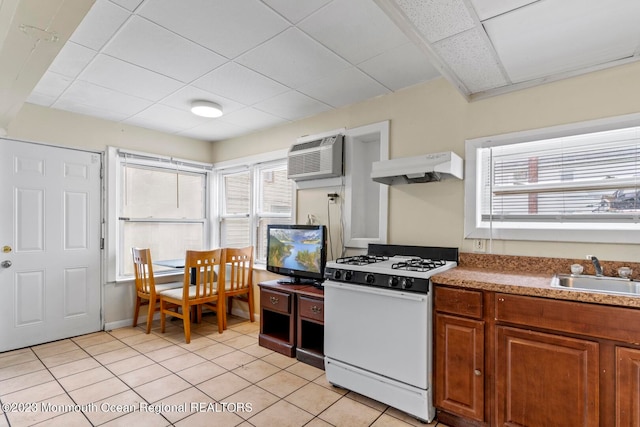 kitchen with custom range hood, sink, white range with gas stovetop, and a healthy amount of sunlight