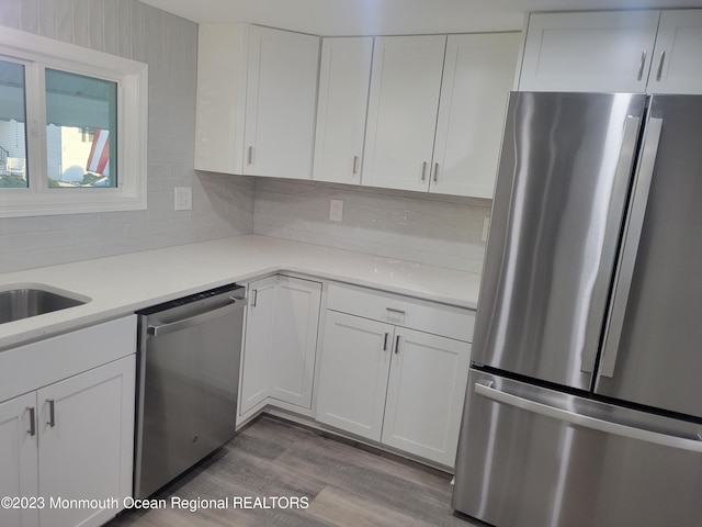 kitchen featuring appliances with stainless steel finishes, white cabinetry, hardwood / wood-style flooring, and tasteful backsplash