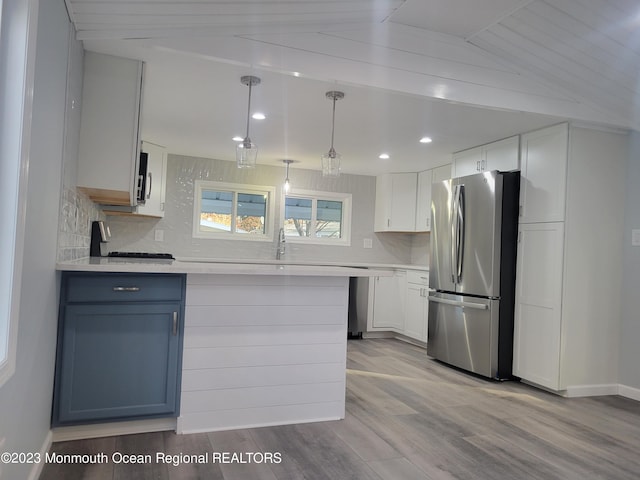 kitchen with light hardwood / wood-style flooring, tasteful backsplash, pendant lighting, appliances with stainless steel finishes, and lofted ceiling