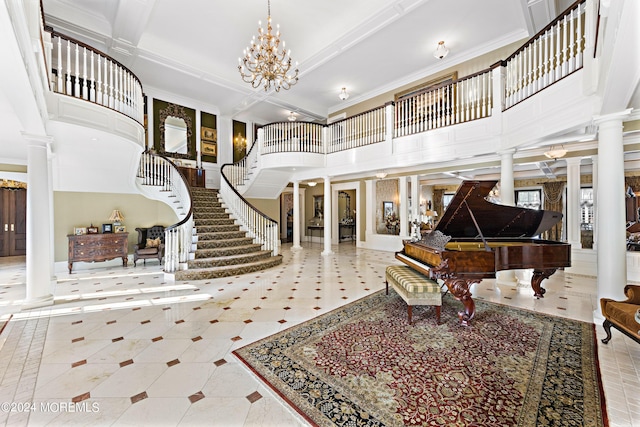 foyer entrance featuring an inviting chandelier, a towering ceiling, decorative columns, and crown molding