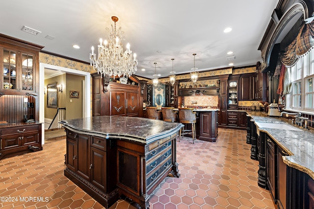 kitchen with crown molding, dark brown cabinets, a center island, and pendant lighting