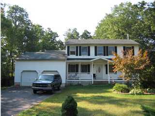 colonial home featuring a front lawn, a porch, and a garage