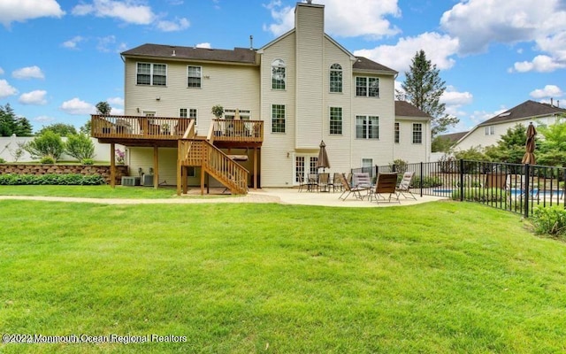 rear view of house with a deck, a patio area, and a yard