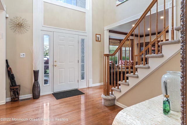 entrance foyer featuring a towering ceiling, hardwood / wood-style flooring, and plenty of natural light