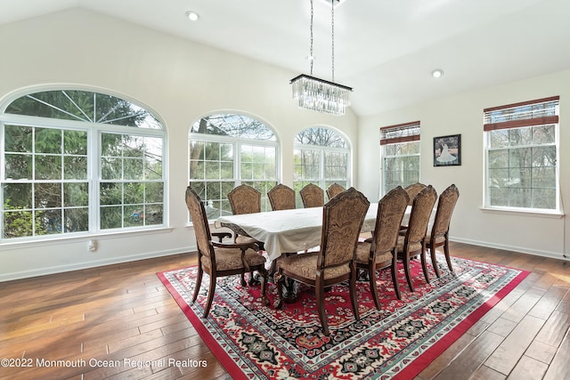 dining area with a chandelier, plenty of natural light, lofted ceiling, and dark hardwood / wood-style floors