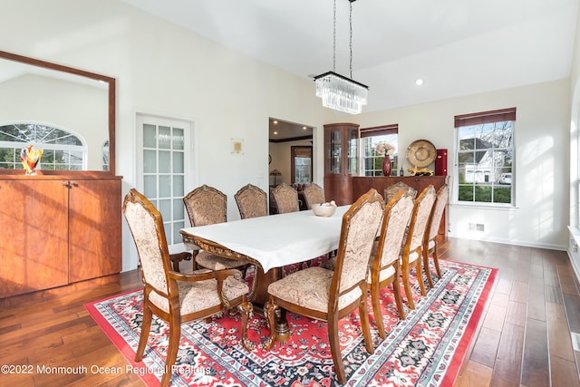 dining room featuring vaulted ceiling, dark hardwood / wood-style floors, and a chandelier