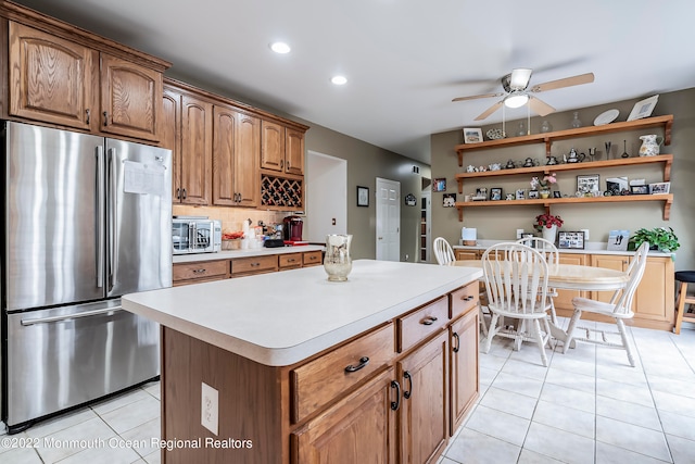 kitchen with ceiling fan, stainless steel refrigerator, light tile floors, and a kitchen island