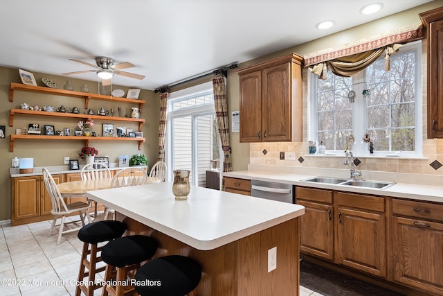 kitchen featuring stainless steel dishwasher, tasteful backsplash, ceiling fan, a breakfast bar, and sink