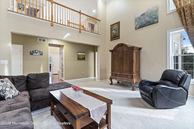 carpeted living room featuring a towering ceiling