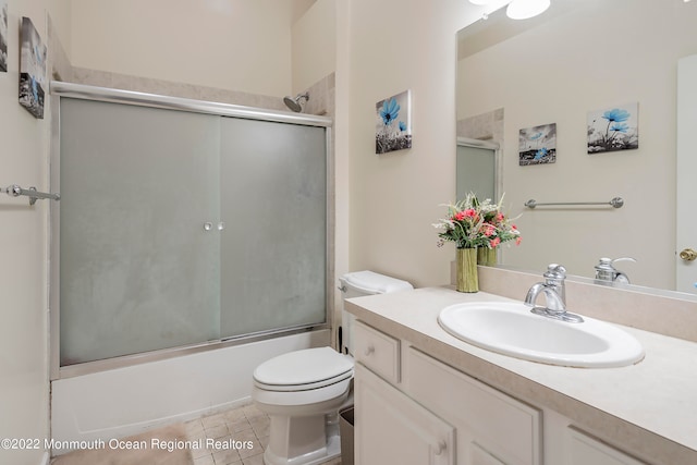 full bathroom featuring tile flooring, shower / bath combination with glass door, toilet, and vanity with extensive cabinet space