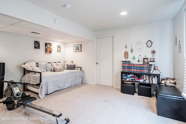 carpeted bedroom featuring a drop ceiling