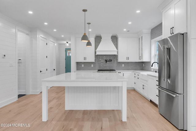 kitchen featuring a kitchen island, light hardwood / wood-style flooring, sink, stainless steel appliances, and custom exhaust hood